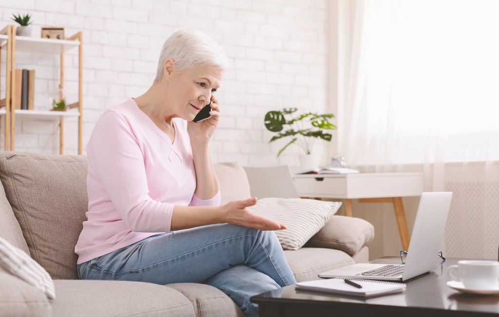 Older woman on phone with laptop